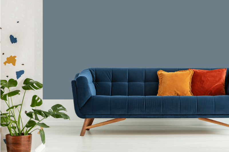 Rainy season on the living room wall behind a deep blue velvet sofa with colorful cushions.