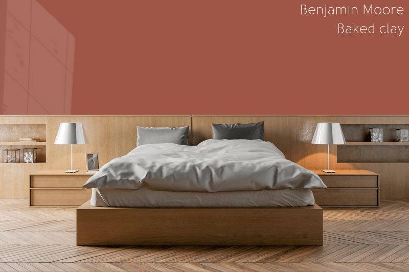 Benjamin Moore Baked Clay on a bedroom wall behind a bed with a wood headboard and grey blankets and pillows.