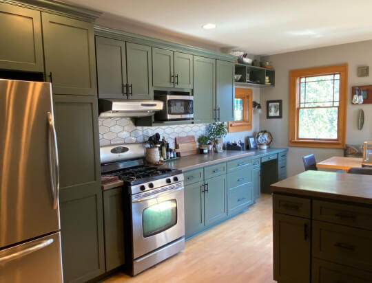 Pewter Green wall of cabinets with white tile, gray countertops, and light gray walls.