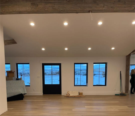 Vaulted living room ceiling with pot lights in a room with Snowbound on walls and ceiling with a tricorn black front door