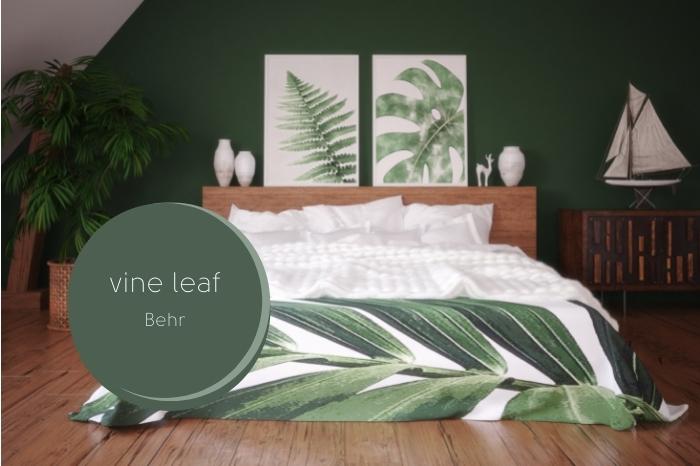 Behr vine leaf over a dark eucalyptus green colored bedroom with wood accents, white bedding, and plant themed accessories and decor.