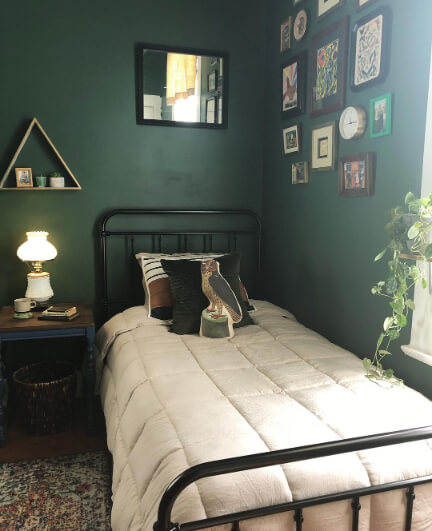 Behr Vine Leaf in a bedroom with a little vintage bed and a gallery wall.