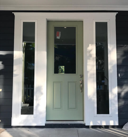 Clary sage on a front door with white trim and black siding