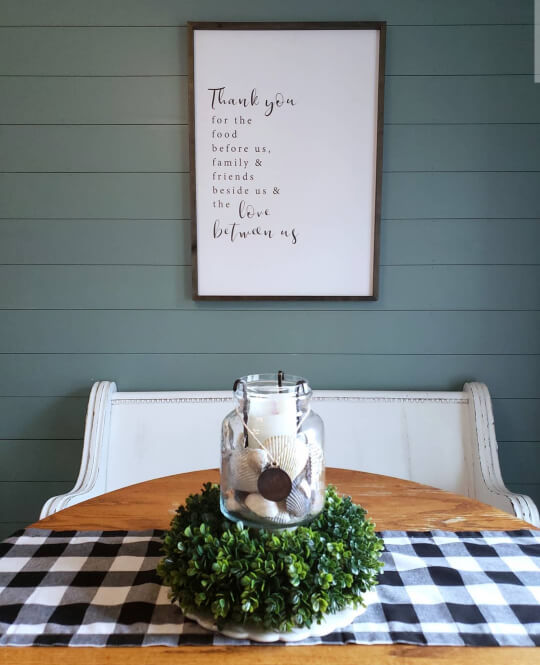 Behr In the Moment - a darker mid toned gray green - on a shiplap wall behind a table