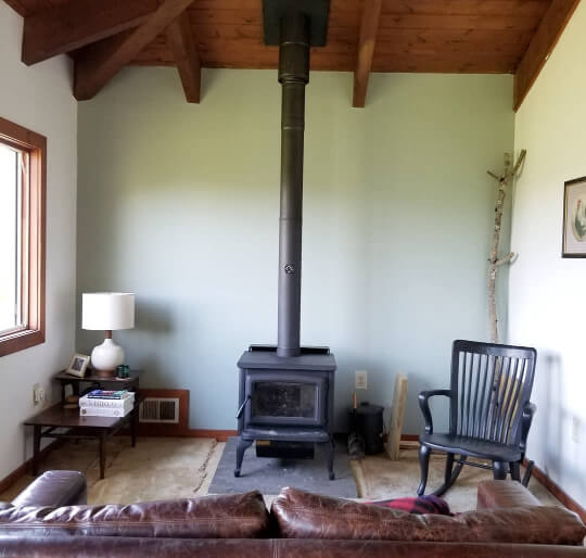 Benjamin moore misted green on a wall behind a wood stove