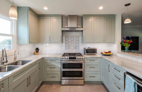 Misted green cabinets with light countertops and white tile and pewter hardware