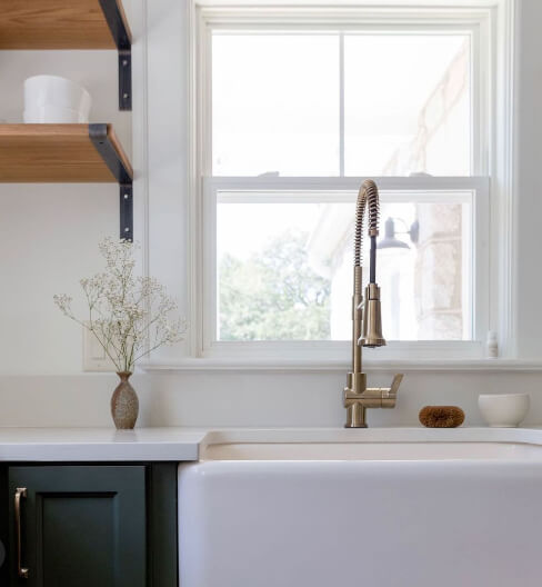 White farmhouse sink, white countertop, and ripe olive cabinets