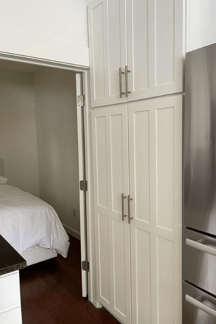 White flour on floor to ceiling pantry cabinets beside a stainless fridge.