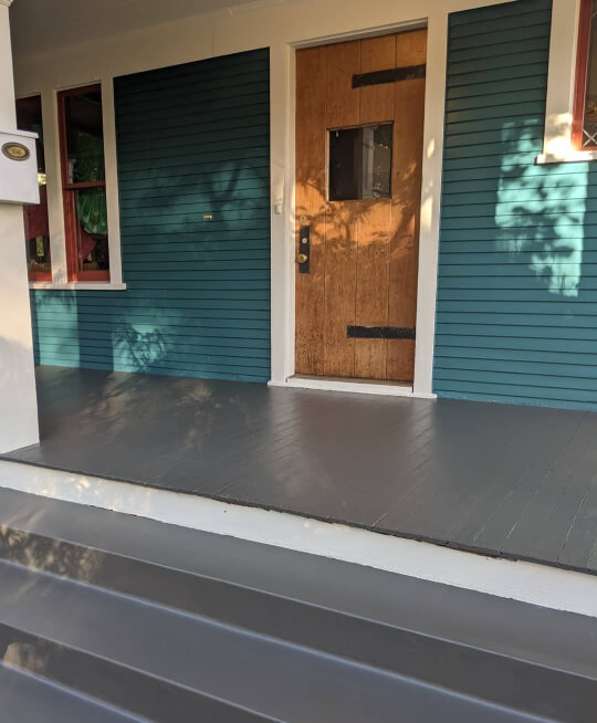 Urbane Bronze porch floor on teal house with steamed milk trim