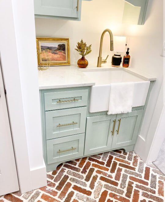 Sea salt on laundry room cabinets with a white farmhouse sink and pure white walls