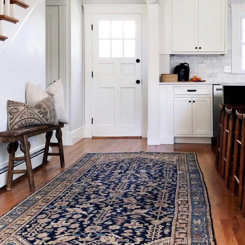 White Flour on kitchen cabinets in a large kitchen with warm wood floors and a long blue rug.