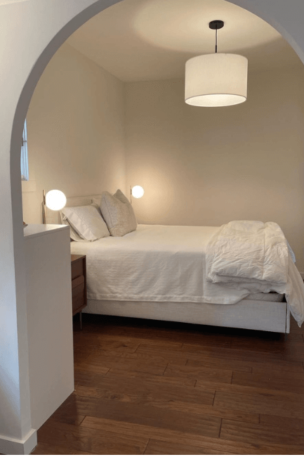 Sherwin Williams White Flour in a bedroom with white bedding and an arched entrance