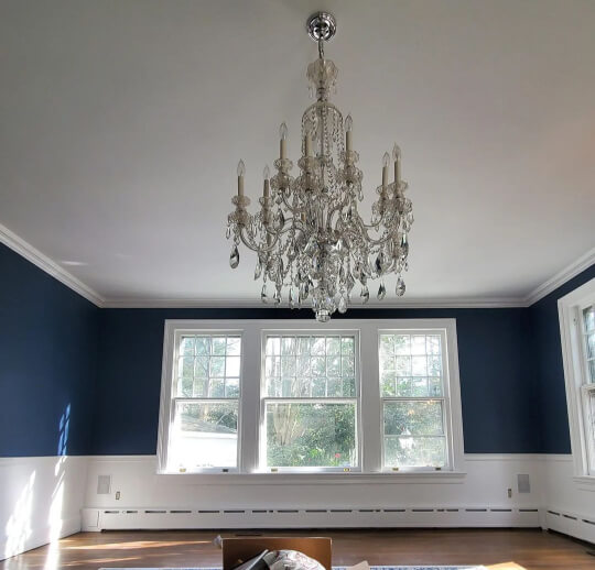 Hale navy living room with warm wood floors and white trim and wainscoting and glass chandelier