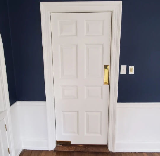 Hale navy living room walls with white door, trim, and wainscoting