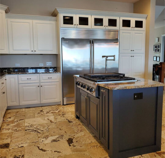 White cabinets with hale navy island and beige stone floors and countertops