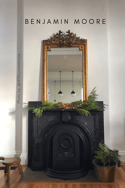 Simply white on a wall with a black iron fireplace and brass mirror
