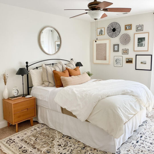 Classic Gray on the walls of a bedroom with white bedding and a gallery wall