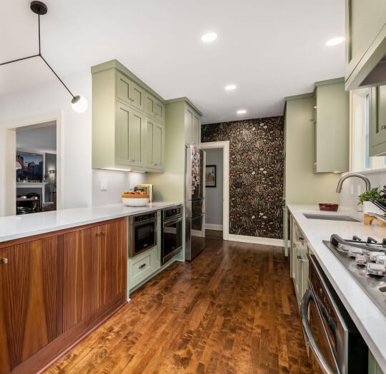 Evergreen fog cabinets in a kitchen with warm wood floors