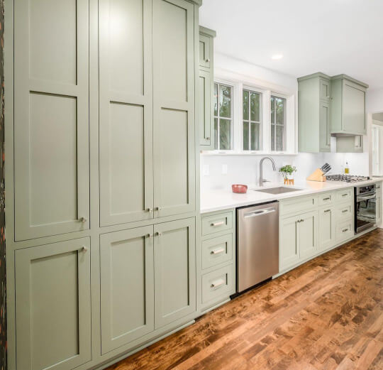 Evergreen fog cabinets in a kitchen with warm wood floors