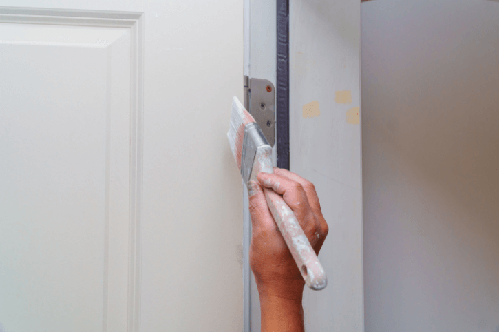 Hand applies paint to door