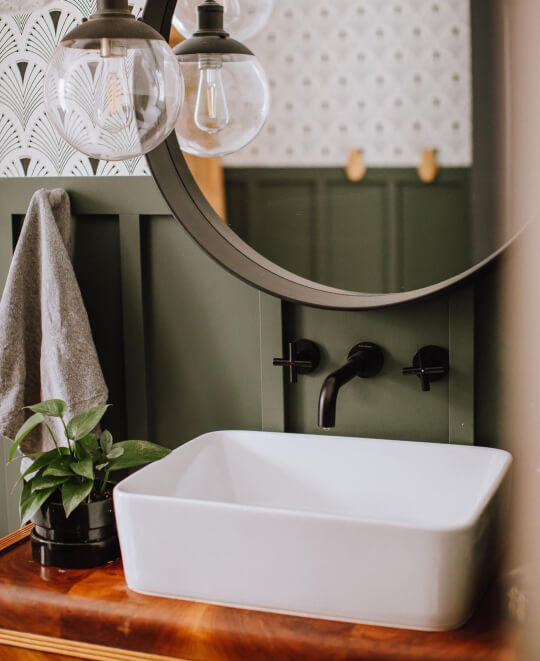 Benjamin Moore Vintage Vogue on Board and Batten wall behind a vintage wood vanity in a bathroom with a white sink and black built-in faucet
