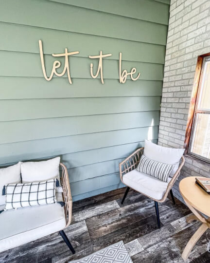 Evergreen Fog on exterior siding on one wall and brick on the other wall in an enclosed porch. There is a sign on the wall that says "let it be."