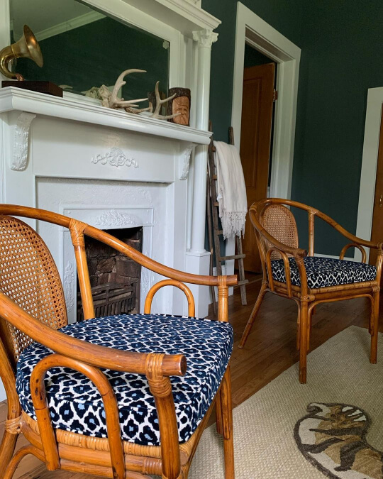 Homburg Gray behind two cane chairs with leopard seat cushions on either side of a white fireplace