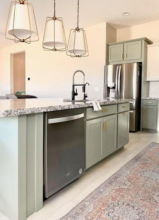 Acacia Haze sage green cabinets with gold hardware and stainless steel appliances