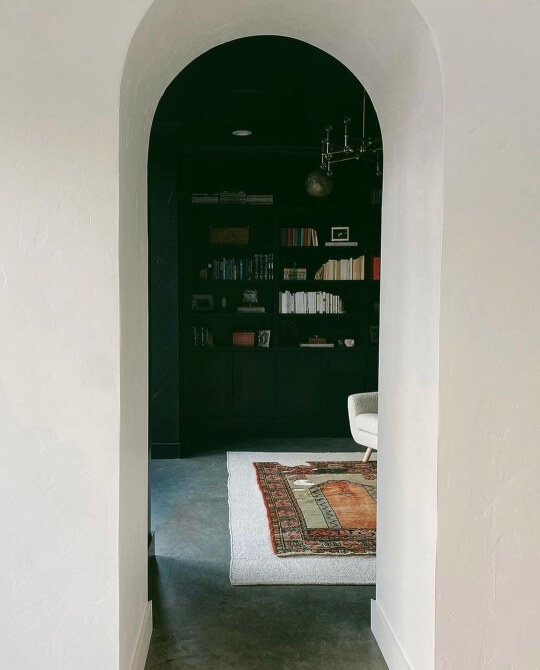 An arched doorway leading into a black forest green living room