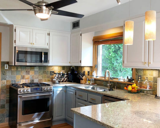 older oak cabinets painted in a two tone white and light blue (Stardew) color scheme with a square slate tile backsplash