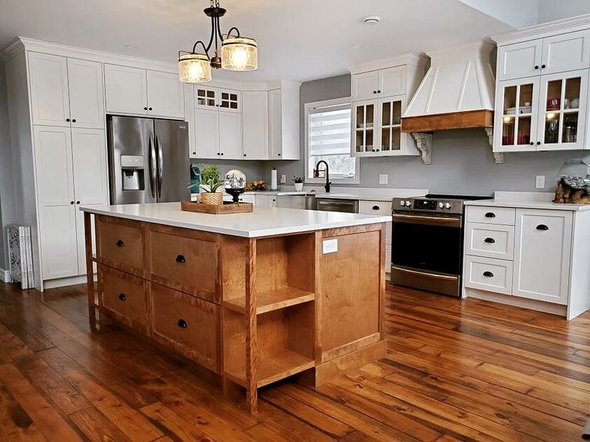 Two toned kitchen with white perimeter cabinets and a birch island stained medium and similar tones floor. White stone countertops
