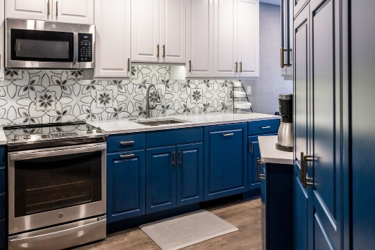 Bright white upper cabinets with indigo lowers and a bold retro floral backsplash