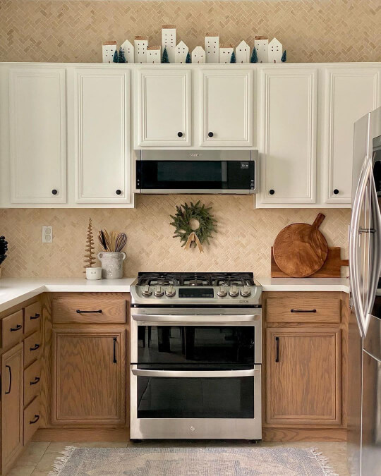 wide shot of Creamy white painted upper cabinets and real oak lowers in a walnut color. Cream herringbone backsplash and white countertops complete the look.