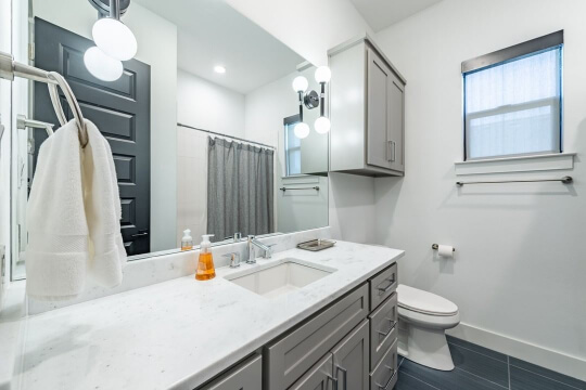 Acier vanity in white bathroom with dark floors