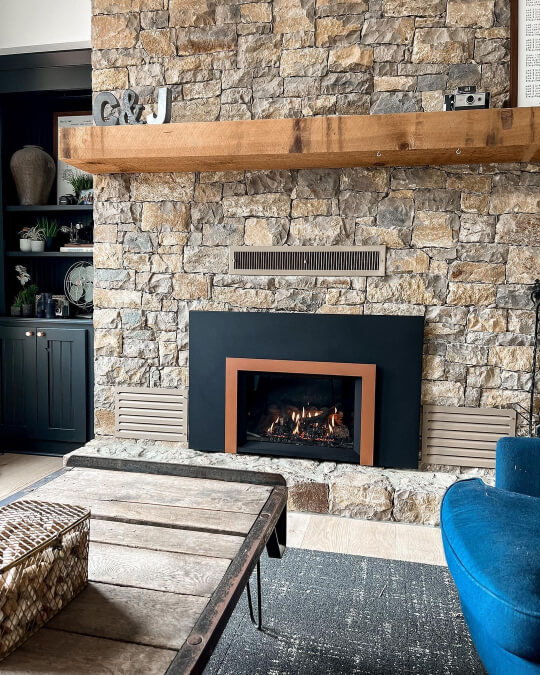 Greenblack Built ins beside a brown and gray stone fireplace