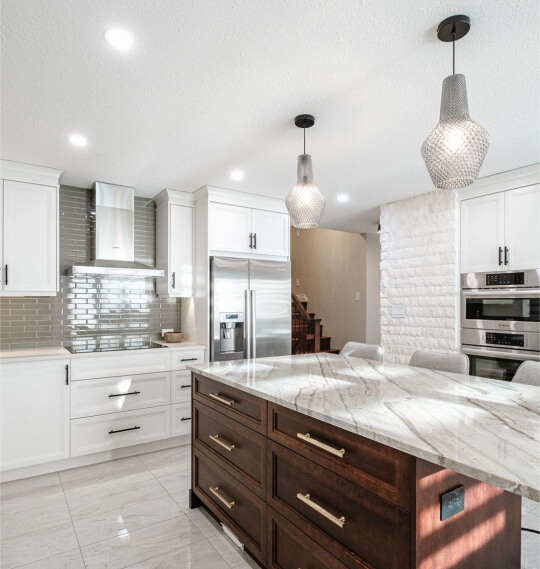 Wood island with gold hardware and contrasting dove wing perimeter cabinets with gray subway tile