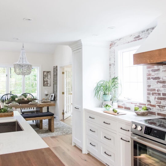 Dove Wing in the dining room in the background of a bright white kitchen with brick backsplash