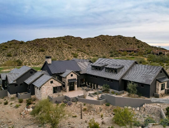 Wide shot of sprawling arizona ranch home with Iron Ore Siding, brick accents, and black roof