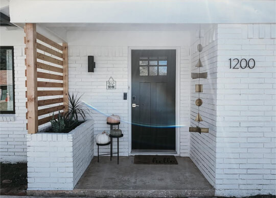Outside entrance area of a pure white brick home with Tricorn black modern door