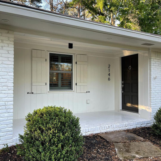 An example of Benjamin Moore Classic Gray on a painted brick Exterior in daylight. Color is Sherwin Williams White Duck with Urbane Bronze on the door.