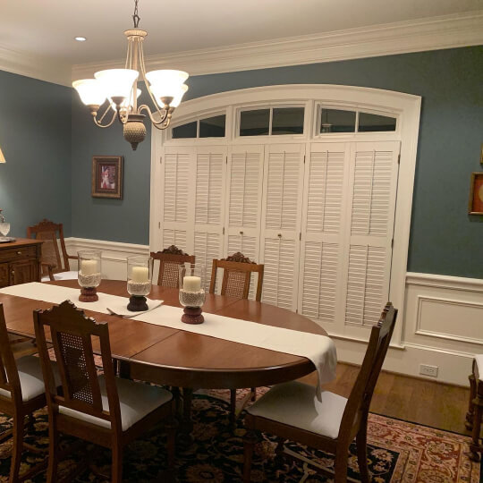 Foggy Day walls with bright white trim, wainscoting, and ceiling in a dining room with a long wood table.