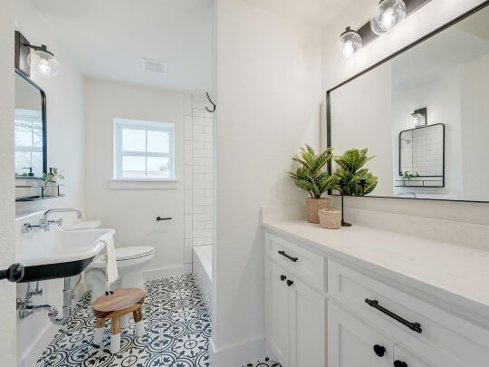 Sherwin Williams shade Alabaster, similar to Behr blank canvas, in a bathroom with white vanity, fun tiled floor, and a black framed mirror above the white sink