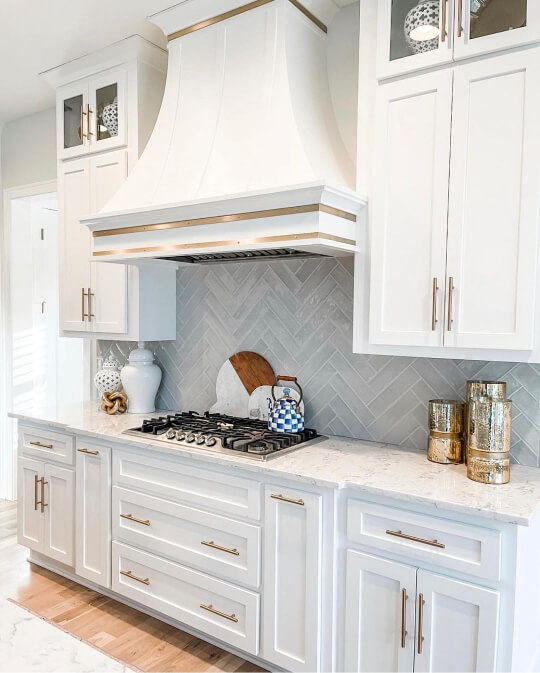 Alabaster on upper and lower cabinets with gold hardware and a gray backsplash
