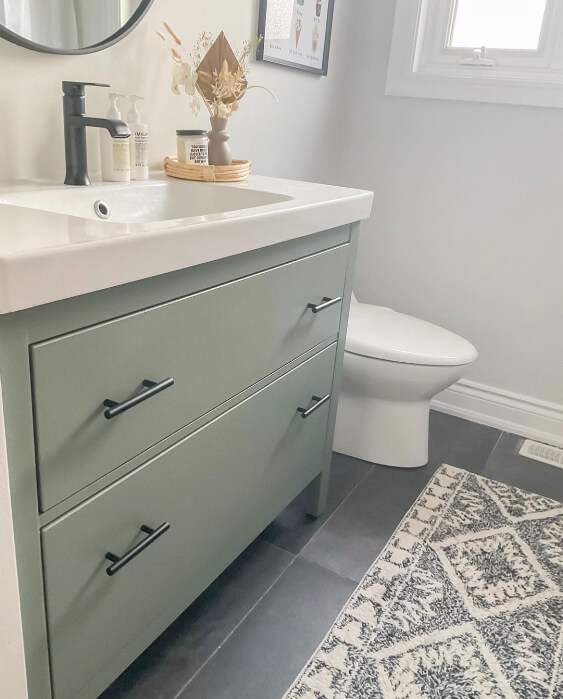 A Sherwin Williams Retreat on a vanity bathroom cabinet beside toilet bowl and Moroccan rug