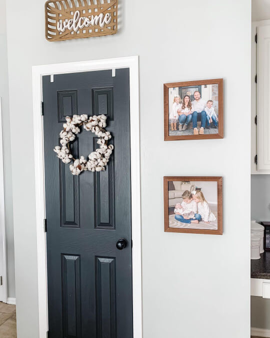 White Metal on a small wall with a charcoal door in the middle and framed photos around it.