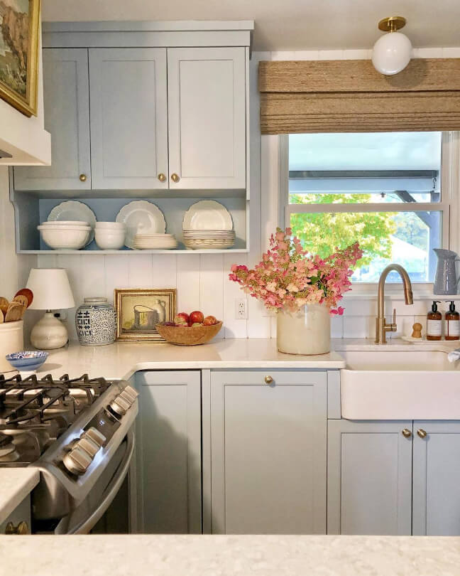 Soft blue cabinets similar to how Behr Light French Gray would look in a kitchen with creamy white walls