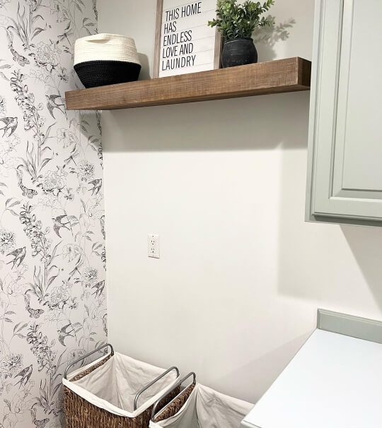 Oyster Bay on cabinets beside laundry ratan basket with plants and birds wallpaper on the left side.