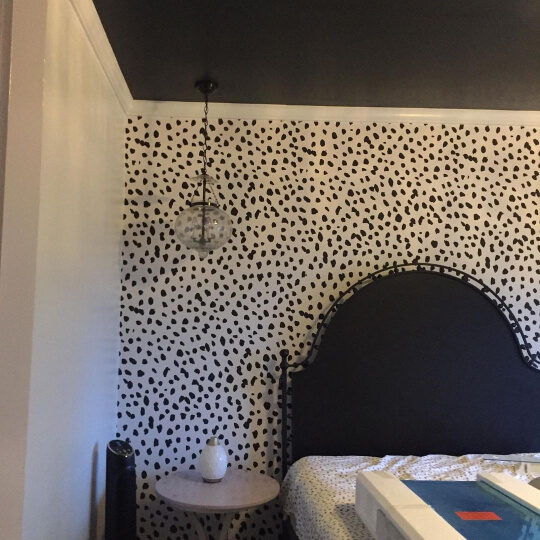 Black Ceiling in a bedroom with animal print wallpaper behind a black headboard