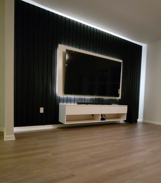 Lit TV wall made with wood slats and painted in black