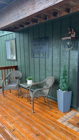 Sherwin Williams Ripe Olive on wide wooden siding behind a cedar deck with chairs for two set up
